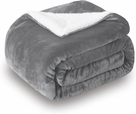 Couverture en gris doux avec une texture en peluche et une doublure blanche.